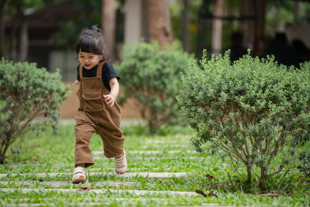happy toddler girl running on a stone pathway in gardenの写真素材