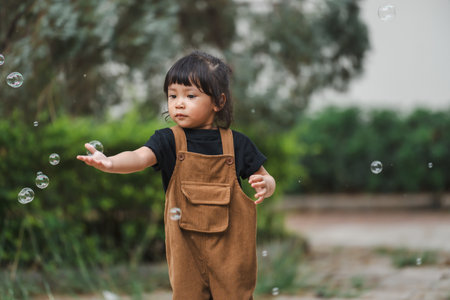 toddler girl playing soap bubble in the parkの写真素材