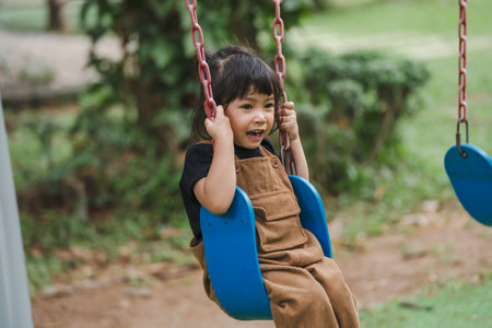 cheerful toddler girl playing on a swingの写真素材