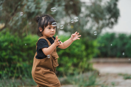 toddler girl playing soap bubble in the parkの写真素材