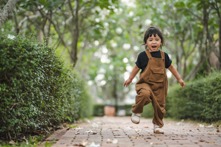 happy toddler girl running on a pathway in gardenの写真素材