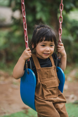 cheerful toddler girl playing on a swingの写真素材