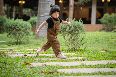happy toddler girl walking on a stone pathway in gardenの写真素材