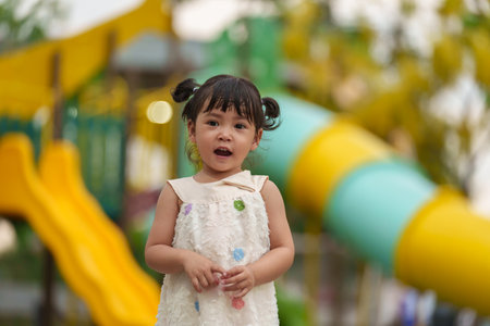 happy toddler girl playing at a outdoor playground in the parkの写真素材