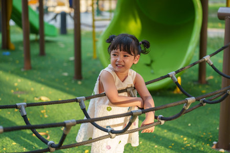 happy toddler girl playing with climbing ropes net at a outdoor playground in the parkの写真素材
