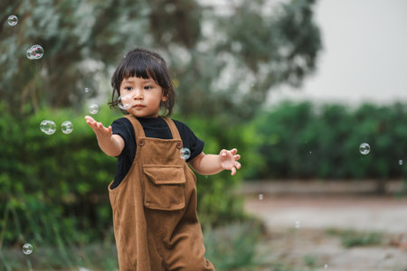 toddler girl playing soap bubble in the parkの写真素材