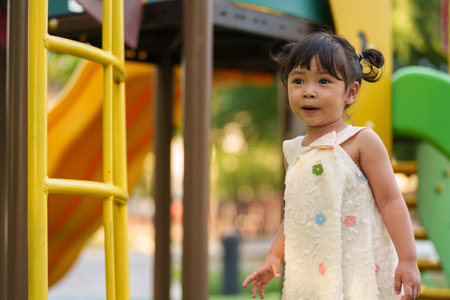 happy toddler girl playing at a outdoor playground in the parkの写真素材