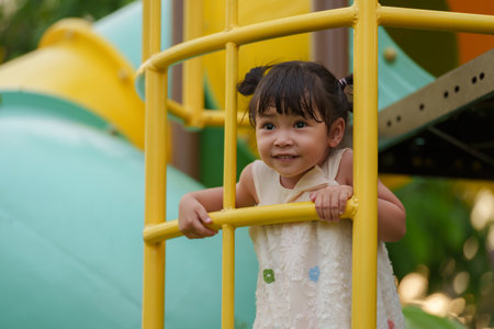 happy toddler girl playing and climbing on outdoor playground at the parkの写真素材