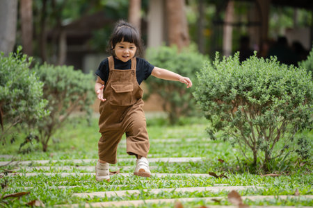 happy toddler girl walking on a stone pathway in gardenの写真素材