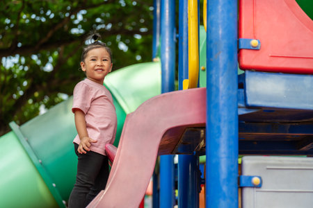 happy toddler girl playing at a outdoor playground in the parkの写真素材