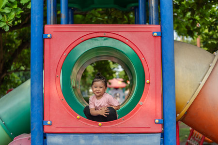 happy toddler girl playing at a outdoor playground in the parkの写真素材