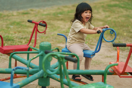 toddler girl having fun while playing on carousel at outdoor playgroundの写真素材