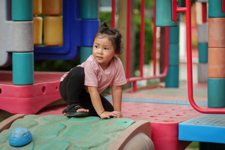 happy toddler girl playing at a outdoor playground in the parkの写真素材