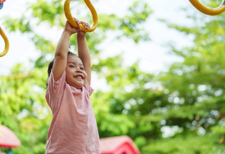 toddler girl hanging on playground rings in the parkの写真素材