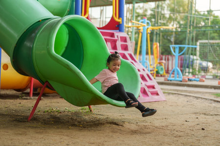 happy toddler baby girl sliding and playing at outdoor playgroundの写真素材