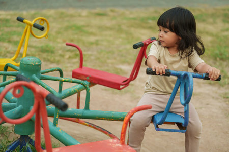 toddler girl having fun while playing on carousel at outdoor playgroundの写真素材