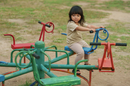toddler girl having fun while playing on carousel at outdoor playgroundの写真素材