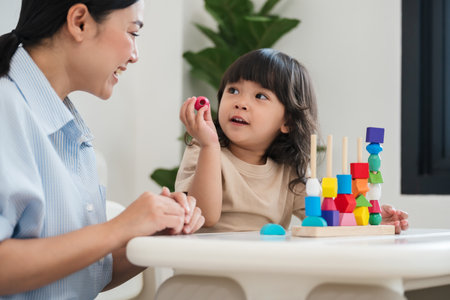 toddler girl and her mother playing educational wooden toy at homeの写真素材