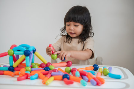 toddler girl playing colorful construction toy at homeの写真素材