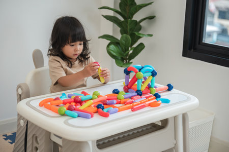 toddler girl playing colorful magnetic construction toy at homeの写真素材