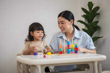 toddler girl and her mother playing educational wooden toy at homeの写真素材