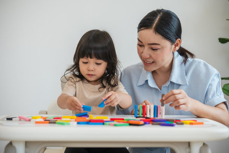toddler girl and her mother playing colorful wooden block toy or domino game togetherの写真素材