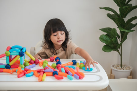 toddler girl playing colorful magnetic construction toy at homeの写真素材