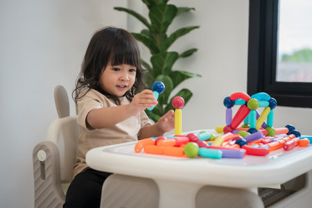 toddler girl playing colorful magnetic construction toy at homeの写真素材