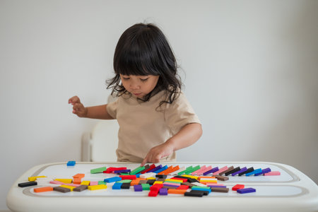 toddler girl playing colorful wooden block toy or domino gameの写真素材