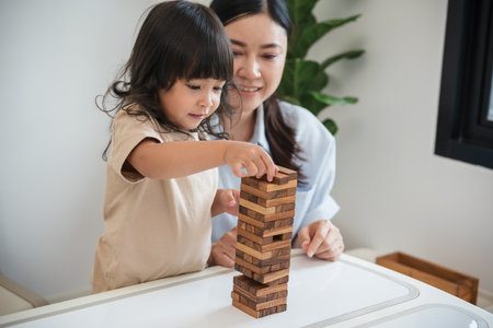 toddler girl with her mother playing wooden block toy togetherの写真素材
