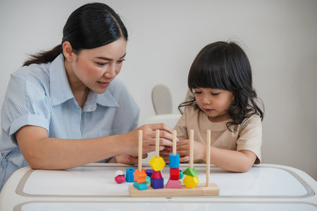 toddler girl and her mother playing educational wooden toy at homeの写真素材