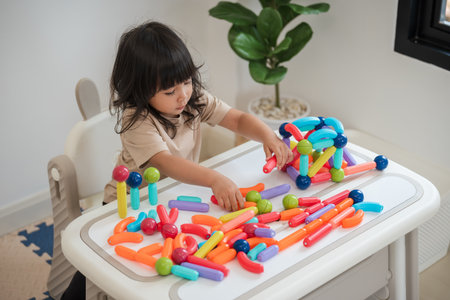 toddler girl playing colorful magnetic construction toy at homeの写真素材