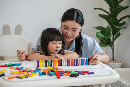 toddler girl and her mother playing colorful wooden block toy or domino game togetherの写真素材