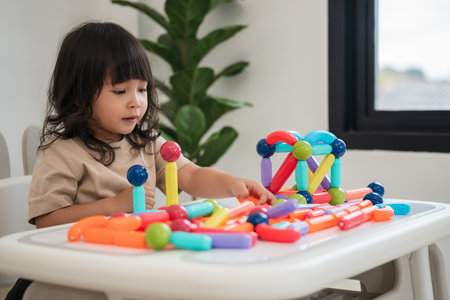 toddler girl playing colorful magnetic construction toy at home