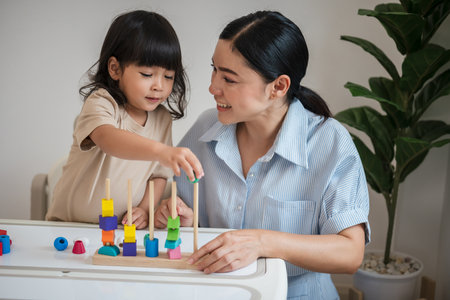 toddler girl and her mother playing educational wooden toy at homeの写真素材