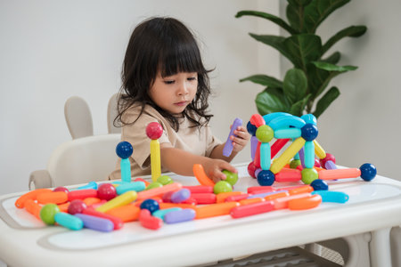 toddler girl playing colorful magnetic construction toy at homeの写真素材