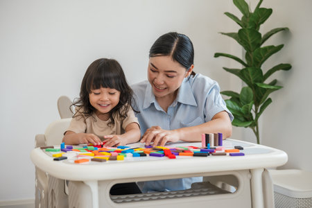 toddler girl and her mother playing colorful wooden block toy or domino game togetherの写真素材