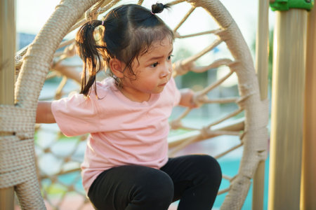 happy toddler girl playing rope tunnel at a outdoor playground in the parkの写真素材