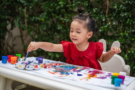 happy toddler girl painting watercolor in a paper at backyard.の写真素材