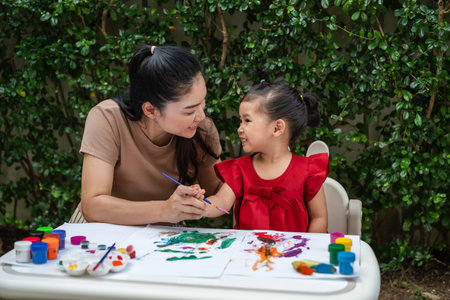 happy mother and toddler girl painting watercolor in a paper at backyard.の写真素材