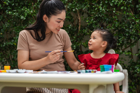 happy mother and toddler girl painting watercolor in a paper at backyard.の写真素材