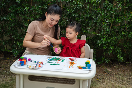 happy mother and toddler girl painting watercolor in a paper at backyard.の写真素材