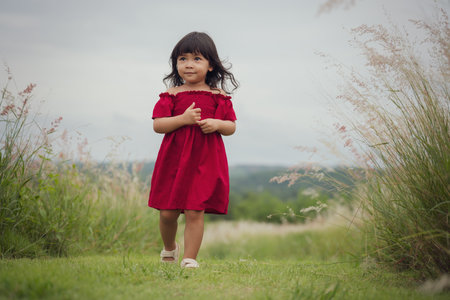 happy toddle girl walking on a grass fieldの写真素材