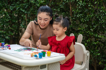 happy mother and toddler girl painting watercolor in a paper at backyard.の写真素材