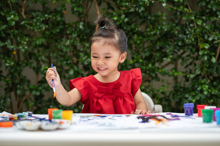 happy toddler girl painting watercolor in a paper at backyard.の写真素材