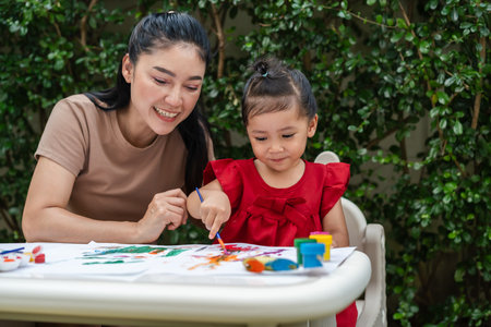 happy mother and toddler girl painting watercolor in a paper at backyard.の写真素材