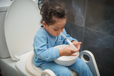 toddler girl washing nasal with syringe and saline by herself. cleaning baby noseの写真素材