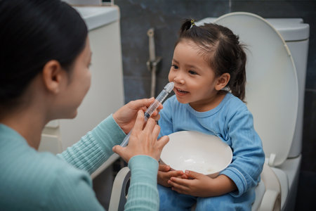 mother making nasal wash for happy toddler girl with syringe and saline. cleaning baby noseの写真素材