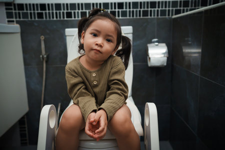 happy toddler girl is sitting on the toilet at home. potty training and learning
