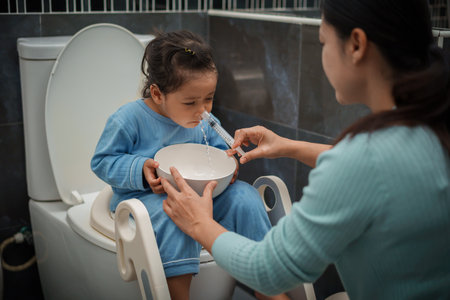 mother making nasal wash for toddler girl with syringe and saline. cleaning baby noseの写真素材